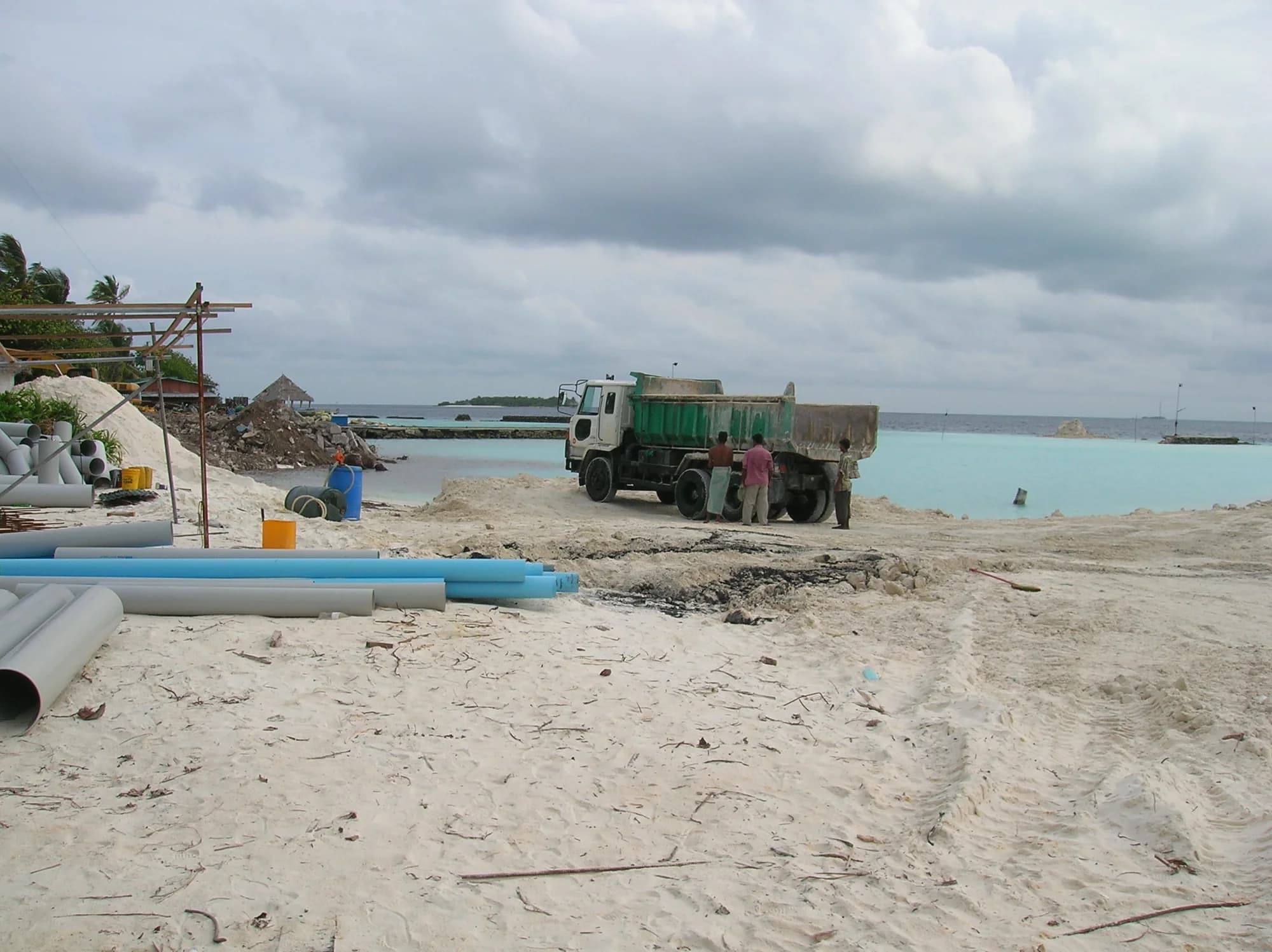 A tipper truck on the reclaimed bank with lengths of pipe staged in the foreground