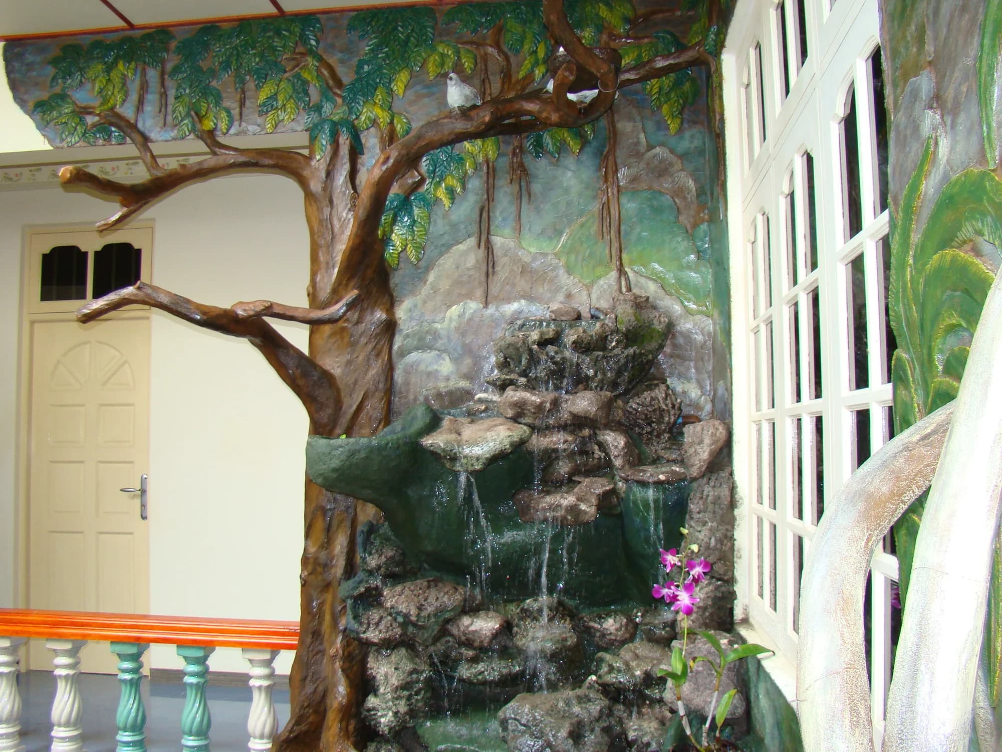 Hand-sculpted tree and tiered rockery waterfall set against a painted forest mural