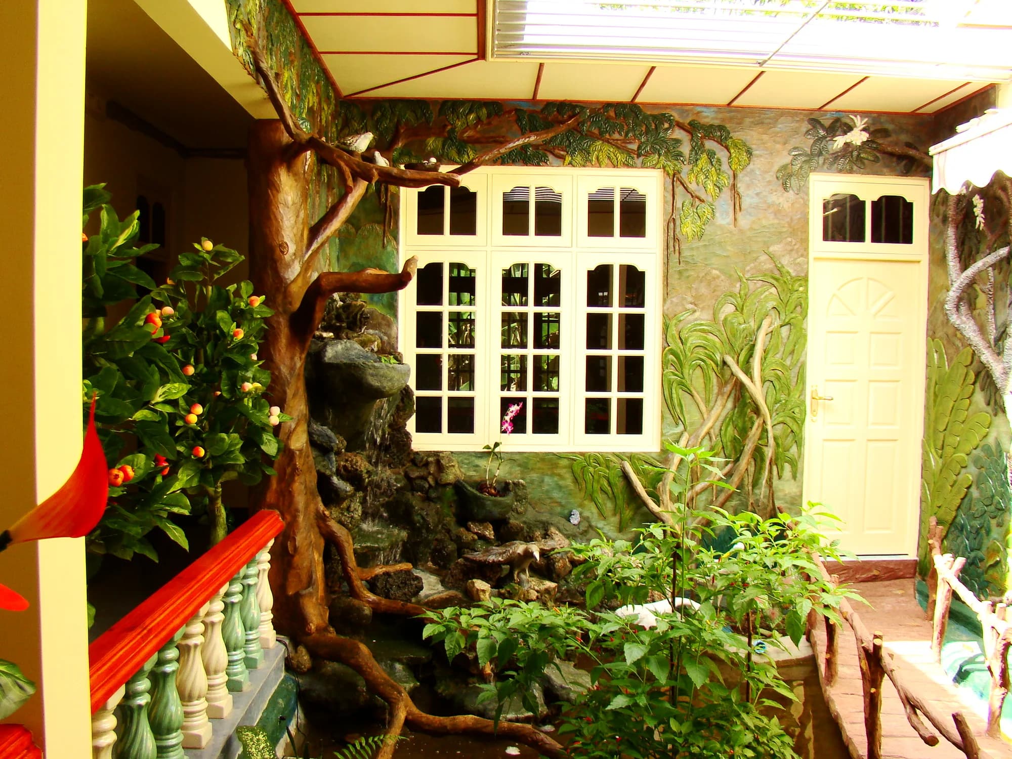 Covered veranda with sculpted tree-root columns, a rockery waterfall and a jungle relief mural