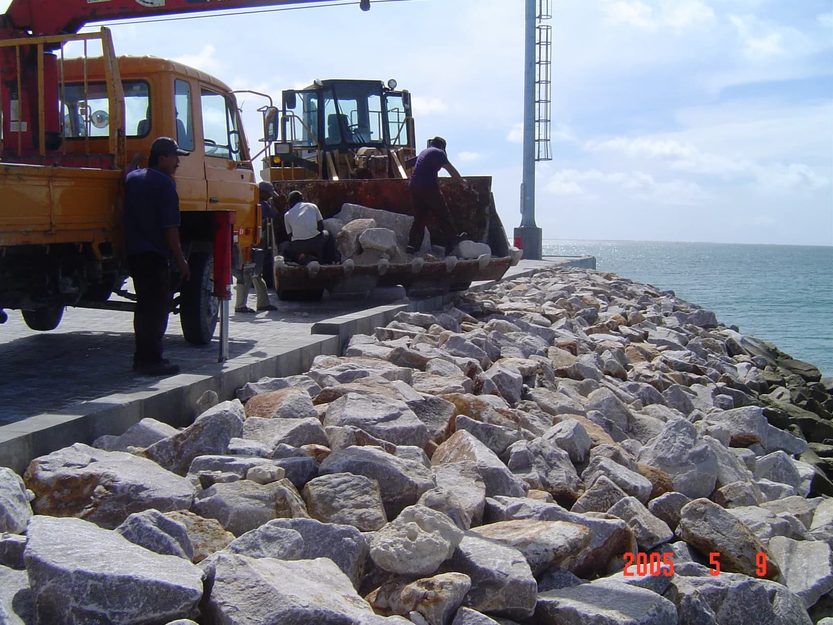 Loader and truck placing rock along a newly built port causeway